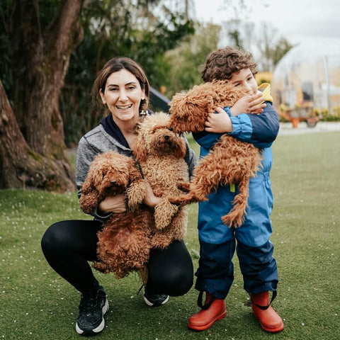 A smiling woman and her young child are enjoying a day outdoors with their three happy dogs in celebration of National Pet Parents Day