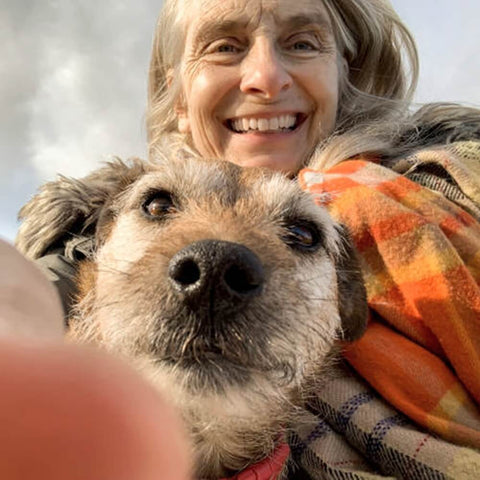 An elderly woman keeping her senior dog safe during winter