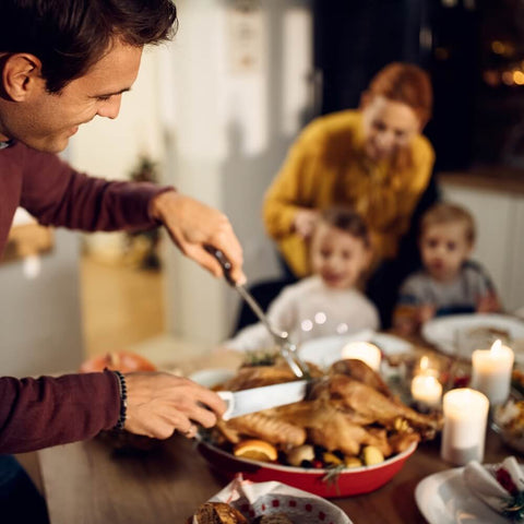 A man carving a Christmas roast at a festive dinner table